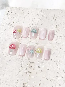 Detail of pink cat eye press-on nails with 3D mushroom accents and glitter finish