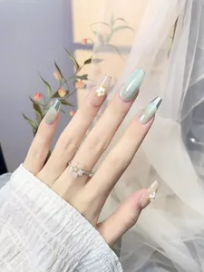 Detail of mint green cat eye press-on nails with silver glitter and 3D floral accents