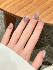 Close-up of handmade cat eye press-on nails in mauve with rhinestones and glitter