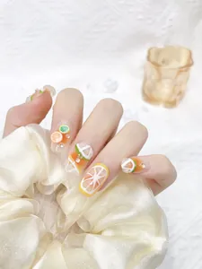 Detail of handmade press-on nails featuring 3D fruit designs and clear rhinestones
