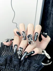 Close-up of handmade black coffin nails with silver butterfly and metallic charms