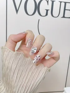 Detail of pink cat-eye press-on nails with luxury rhinestones and polka dot accents