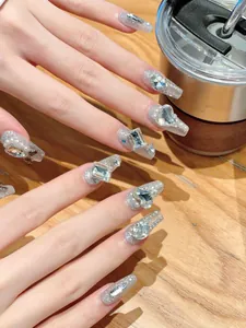 Macro detail of long coffin nails with silver glitter, rhinestones, pearls and metallic cross