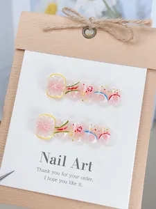 Detalle de uñas artesanales con diseños de limón y pomelo presentadas en su estuche