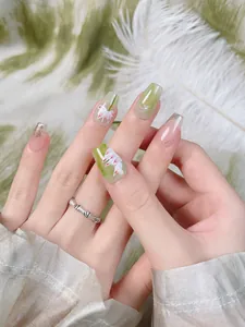 Dettaglio di unghie finte con motivo marmo verde e decorazioni floreali a giglio
