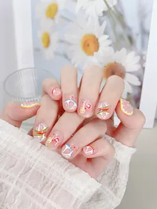 Detalle de uñas postizas cortas hechas a mano con diseños de frutas de limón y pomelo