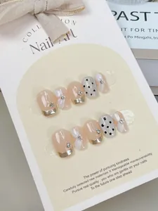 Détails d'ongles press-on avec bords dorés, fleurs 3D et motifs à pois noirs élégants