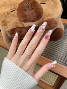 Detail of handmade press-on nails featuring 3D bear, heart patterns and a pearl ring