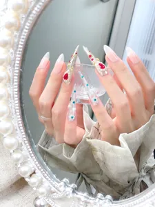 Makro-Detail verzierter Stiletto-Nägel mit roten Kristallen und Perlen