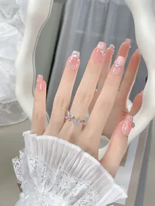 Detail of pink gradient press-on nails with 3D butterfly, rhinestones and pearls