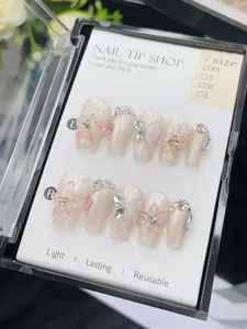 Detail of handmade press-on nails with 3D butterfly, floral art, and rhinestones in a box