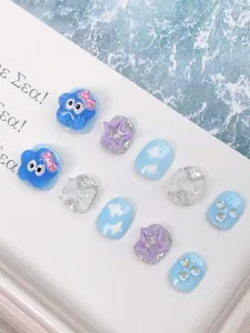 Detail of handmade cartoon press-on nails with blue clouds and 3D star characters