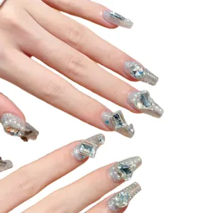 Sparkly handmade press-on nails with silver glitter, rhinestones, and pearls on white backdrop