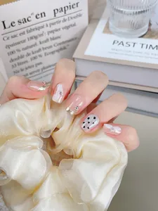 Vue détaillée d'ongles faits main avec bordures dorées françaises et nœuds en relief