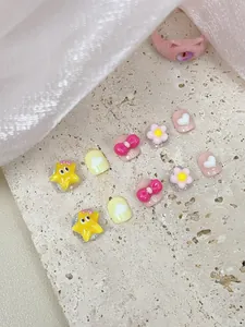 Macro shot of 3D resin cartoon nail art charms featuring stars, hearts and bows