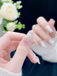 Macro detail of nude pink press-on nails with 3D cherry blossom and sparkling rhinestones