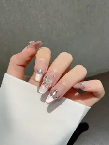 Detail of pink cat-eye press-on nails with 3D butterfly and rhinestone accents