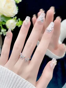 Detailed view of nude gradient press-on nails with silver butterfly ring on mirror