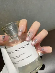 Detailed view of pink cat eye press-on nails with 3D crystal rhinestones and butterfly art