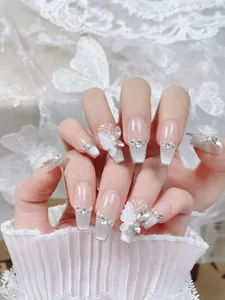 Detalle de uñas postizas ojo de gato blancas con mariposas 3D y pedrería brillante plata
