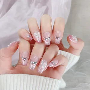 Dettaglio di unghie finte pink cat-eye con farfalle 3D bianche e strass scintillanti