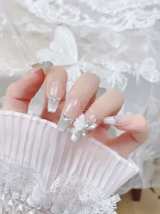 Vista detallada de uñas postizas francesas con mariposas 3D y perlas de lujo