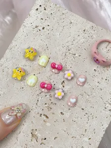 Detail of macaron press-on nails with star, flower, and heart motifs plus a monster ring