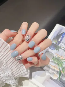 Detailed view of light blue press-on nails with rhinestone accents and glossy finish