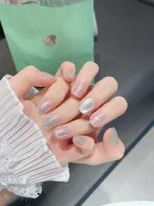 Dettaglio di unghie finte glitterate cat-eye con paillettes iridescenti in forma quadrata