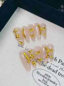 Vue détaillée d'ongles faits main avec strass en cœur jaune et perles argentées brillantes