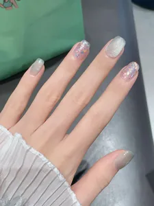 Dettaglio unghie finte fatte a mano effetto cat-eye con paillettes e glitter verdi