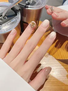 Detail of handmade cat-eye press-on nails with amber rhinestones and glitter