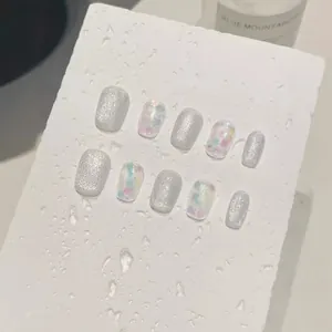 Sparkling silver cat eye press-on nails with heart sequins on a white stone stand