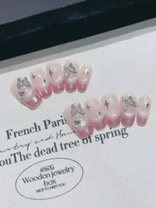 Detail of handmade pink ombre press-on nails with silver butterfly and star charms