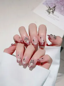 Close-up of handmade pink cat-eye press-on nails with 3D metal butterfly ornaments