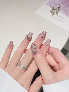 Macro shot of silver butterfly rings and pink French press-on nails with star sequins