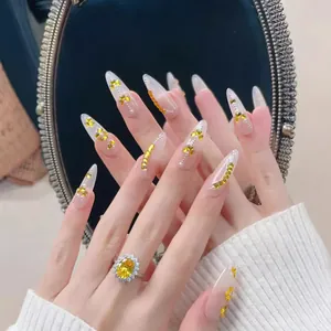 Ongles à presser longs et pointus avec feuille d'or jaune et paillettes de papillon