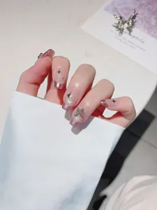Detail of silver glitter French nails with a 3D rhinestone butterfly and black star patterns