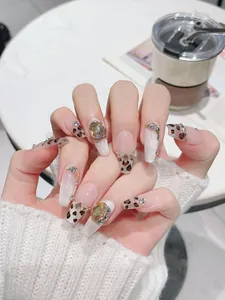 Détail de faux ongles léopard faits main avec gemmes ambrées et effet œil de chat