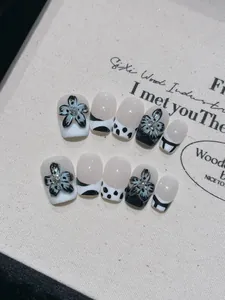 Détail de faux ongles faits main avec fleurs 3D noires, pois et motifs abstraits