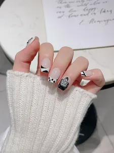 Détail de faux ongles faits main avec fleurs 3D noires et décorations de strass