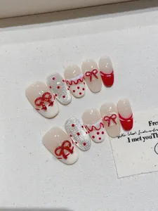 Dettaglio di unghie fatte a mano con fiocchi 3D rossi, pois e glitter scintillanti