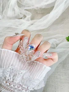 Détail d'ongles longs pointus œil-de-chat avec gemme cœur bleue et strass étincelants