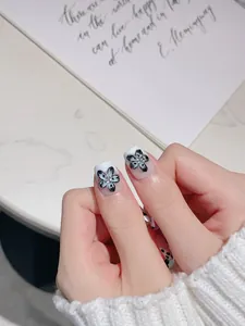 Détail de faux ongles blancs avec fleurs 3D bleu clair et petits strass brillants
