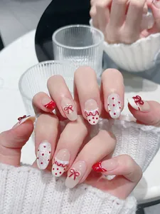 Dettagli di unghie finte fatte a mano con fiocchi 3D rossi, pois e glitter argento