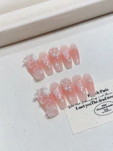 Detail of pink gradient press-on nails with 3D floral, pearl and butterfly charms