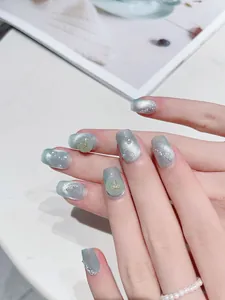 Detail of light blue cat-eye nails with pearls and golden butterfly accents