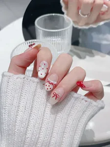 Dettaglio di unghie finte fatte a mano con fiocchi rossi 3D, pois e glitter argento