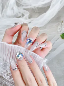 Détail macro de faux ongles stiletto longs avec effet œil-de-chat et strass cœur en 3D
