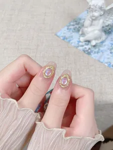 Vue macro d'un bijou d'ongle opale ovale avec cadre doré vintage sur les doigts
